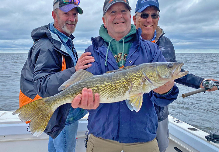 image of border view walleye charter customers holding big fish